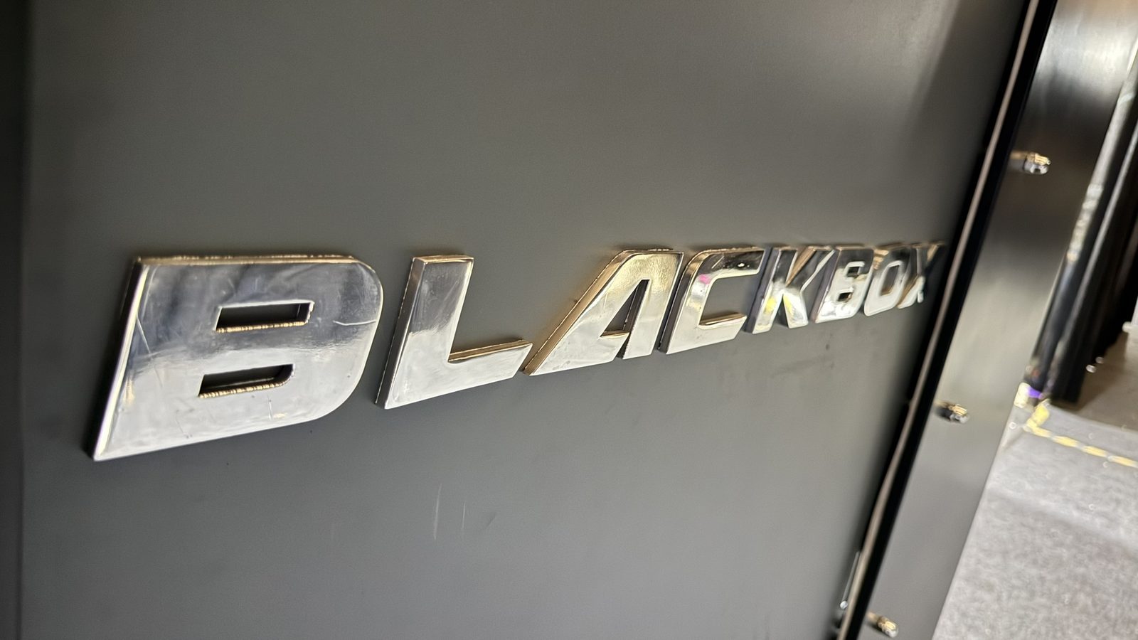 Close-up of the polished BLACKBOX badge on the cabinet panel